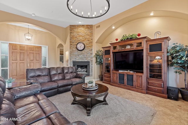 living room featuring a stone fireplace and an inviting chandelier