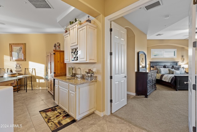 kitchen featuring light stone countertops, sink, light tile patterned floors, and cream cabinetry