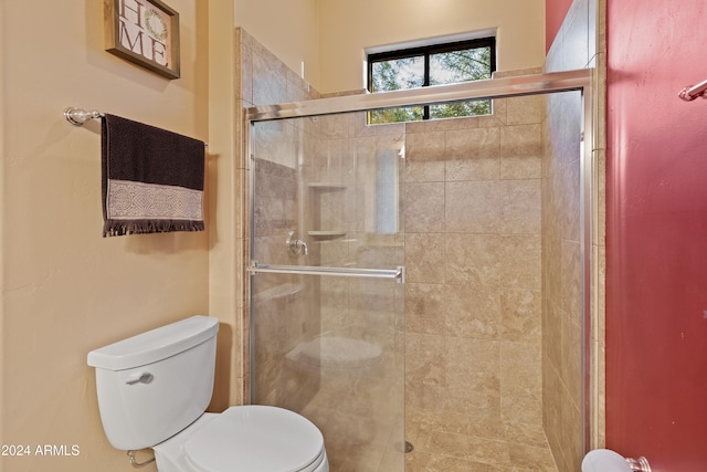 bathroom featuring a shower with shower door and toilet