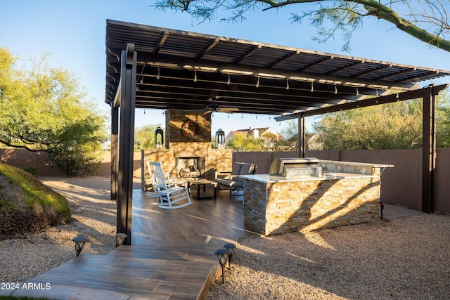 view of patio featuring an outdoor kitchen, an outdoor stone fireplace, a pergola, and grilling area