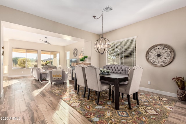 dining room with hardwood / wood-style flooring and ceiling fan with notable chandelier