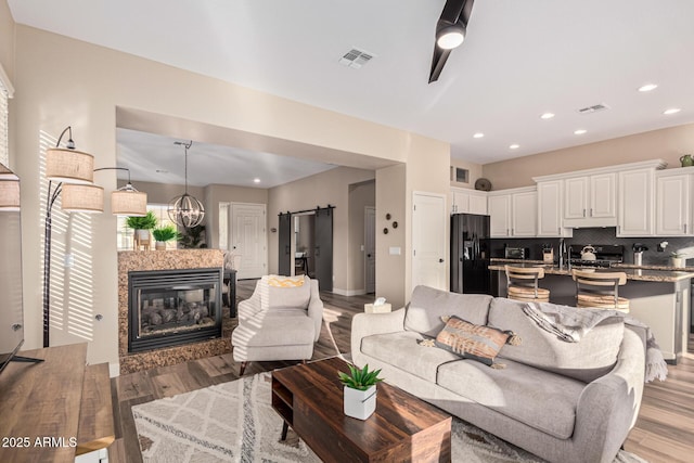 living room featuring a high end fireplace, a barn door, and light wood-type flooring