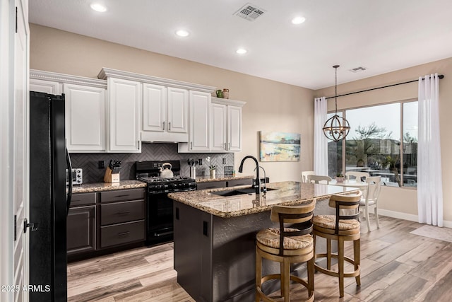 kitchen with white cabinetry, sink, hanging light fixtures, black appliances, and light wood-type flooring