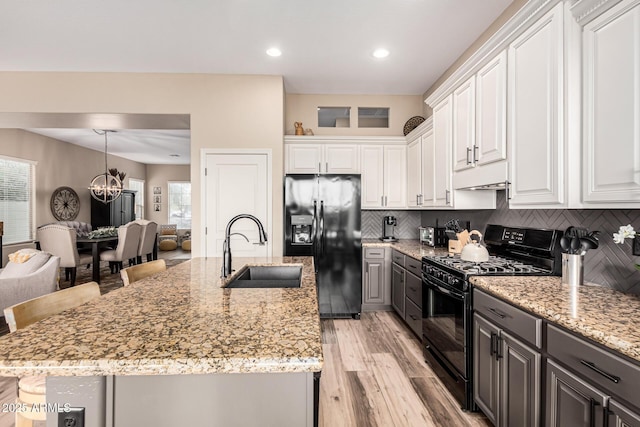 kitchen featuring sink, white cabinets, backsplash, and black appliances