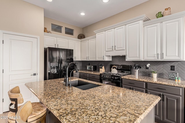 kitchen with sink, a center island with sink, white cabinets, and black appliances