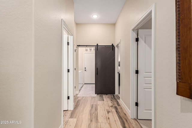 hall featuring a barn door and light hardwood / wood-style floors