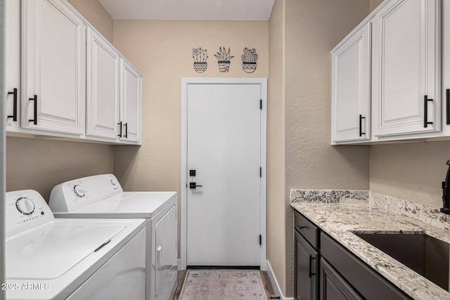 washroom with cabinets, sink, and washing machine and clothes dryer