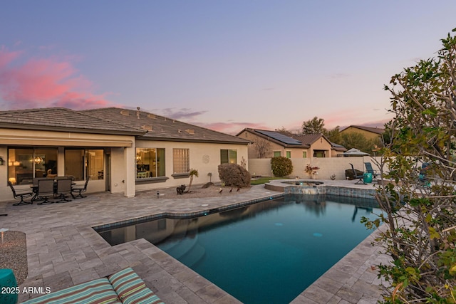 pool at dusk featuring an in ground hot tub and a patio area