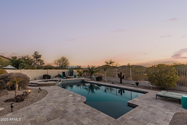 pool at dusk with an in ground hot tub and a patio