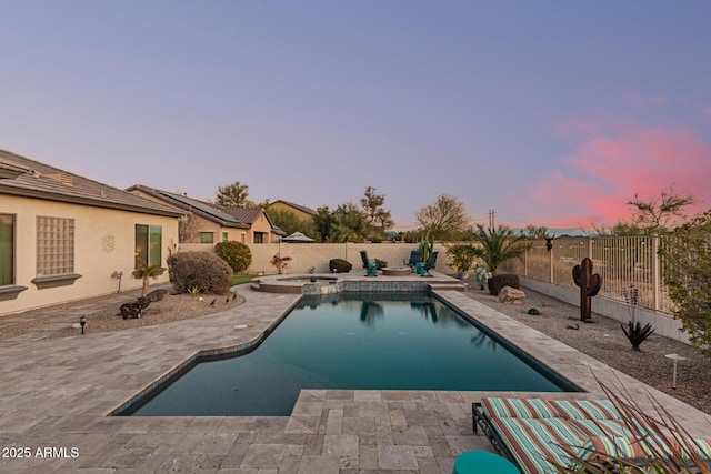 pool at dusk with an in ground hot tub and a patio