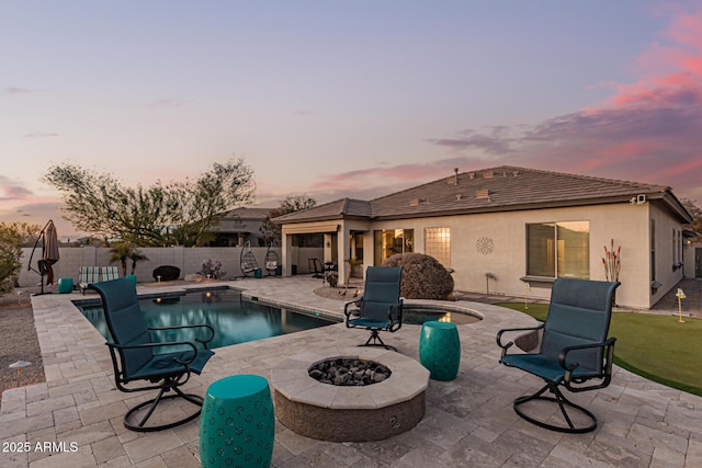 pool at dusk with a patio and a fire pit