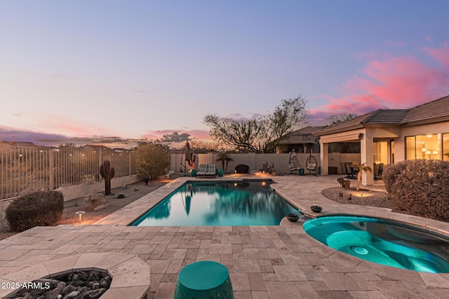 pool at dusk featuring an in ground hot tub, an outdoor fire pit, and a patio