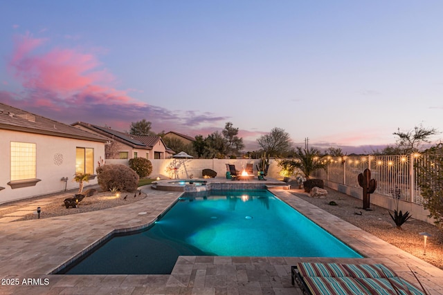 pool at dusk with a patio area and an in ground hot tub