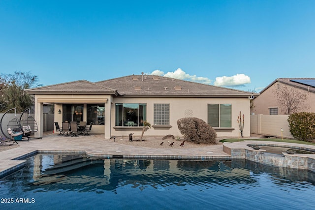 rear view of property featuring a pool with hot tub and a patio