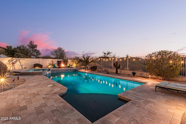 pool at dusk with an in ground hot tub and a patio