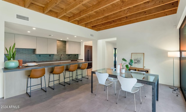 dining room featuring beamed ceiling, wooden ceiling, and sink