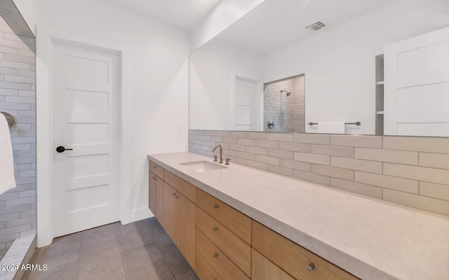 bathroom with tile patterned flooring, vanity, backsplash, and tiled shower