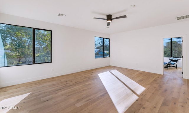 empty room featuring ceiling fan, a healthy amount of sunlight, and light hardwood / wood-style flooring