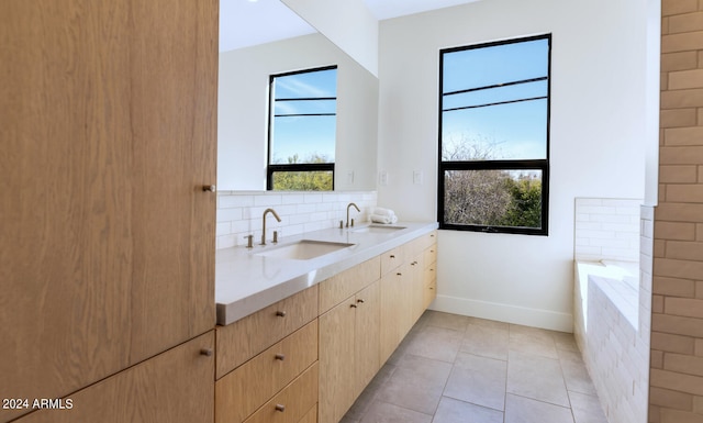 bathroom with tile patterned floors, decorative backsplash, a tub to relax in, and vanity