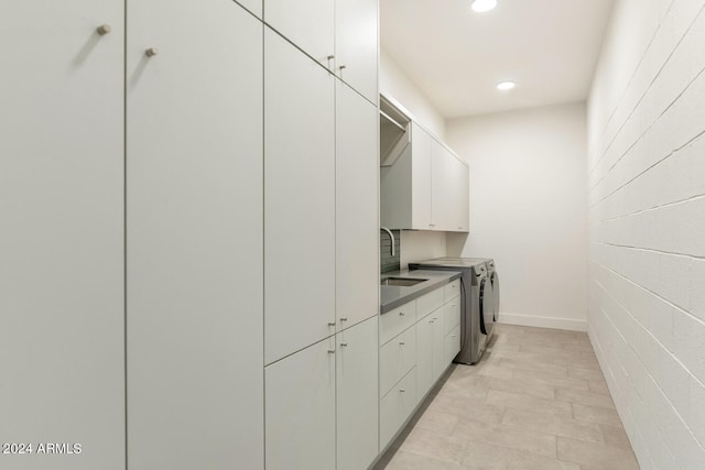 washroom featuring sink, cabinets, and independent washer and dryer