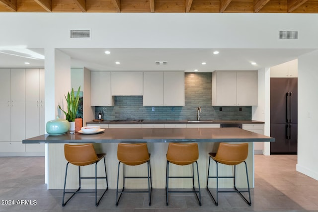 kitchen with white cabinets, a kitchen breakfast bar, sink, high quality fridge, and stovetop