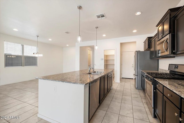 kitchen featuring light tile patterned flooring, hanging light fixtures, appliances with stainless steel finishes, sink, and a center island with sink