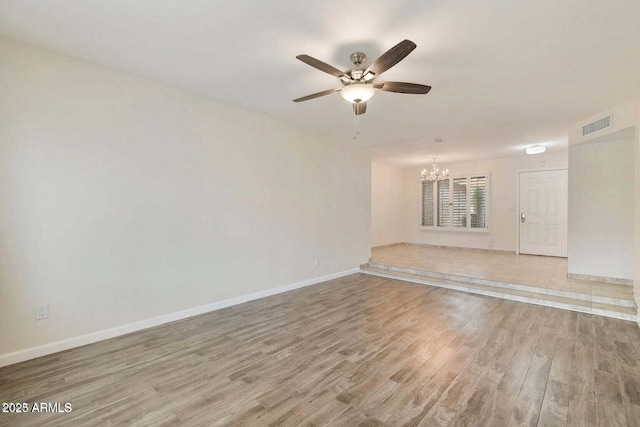 unfurnished room with ceiling fan with notable chandelier and hardwood / wood-style floors