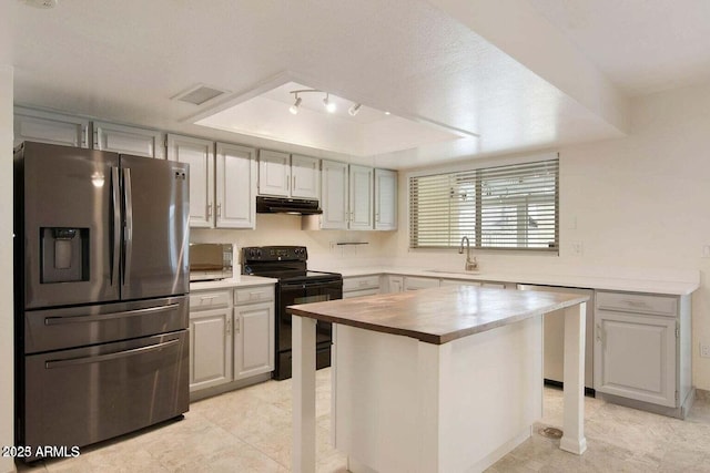 kitchen featuring sink, a kitchen breakfast bar, a raised ceiling, a kitchen island, and stainless steel appliances