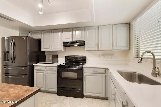 kitchen with black electric range oven, sink, stainless steel refrigerator with ice dispenser, white cabinets, and a raised ceiling