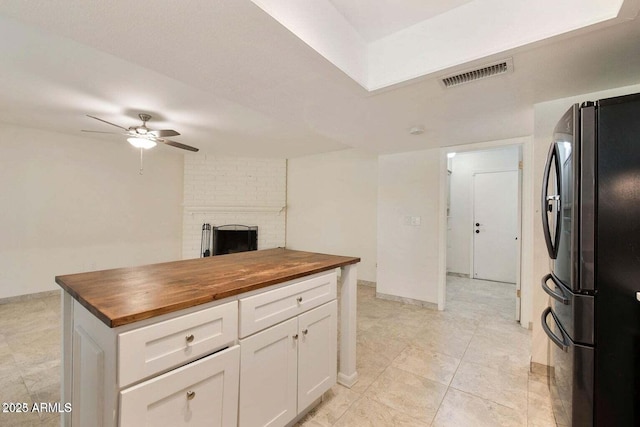 kitchen featuring stainless steel refrigerator, ceiling fan, wooden counters, and white cabinets