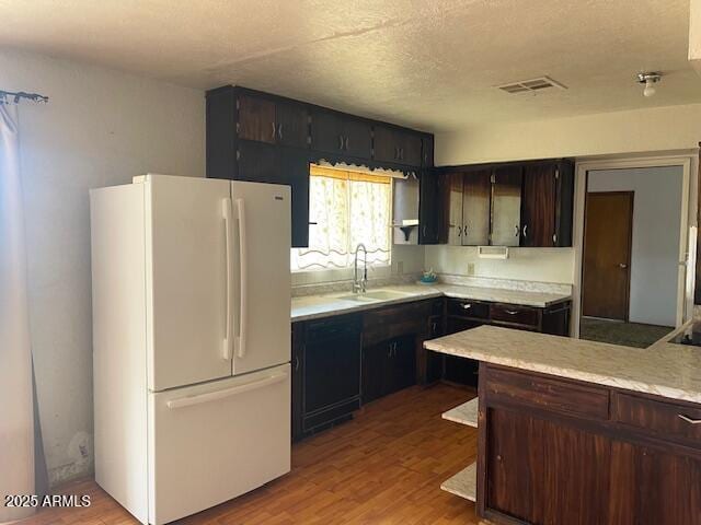 1010 N Florida Ave, Douglas, AZ 85607 - kitchen with freestanding refrigerator, a sink, light countertops, light wood-type flooring, and a textured ceiling