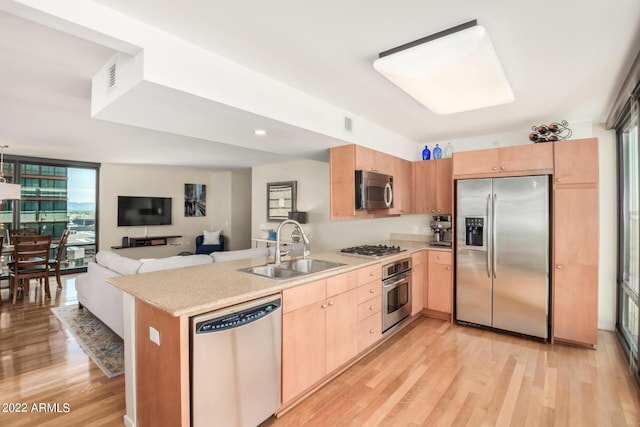 kitchen featuring light hardwood / wood-style floors, kitchen peninsula, sink, light brown cabinets, and stainless steel appliances