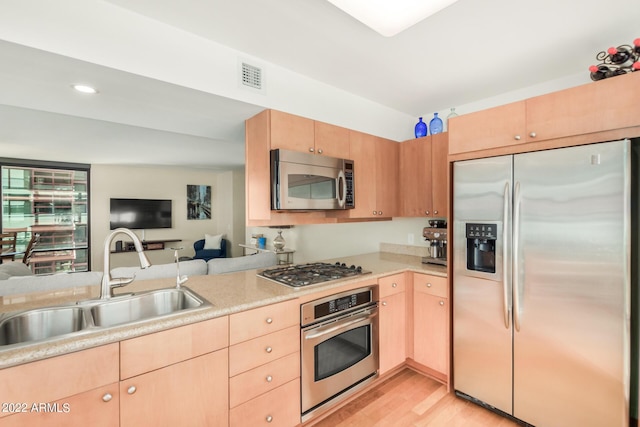 kitchen with light brown cabinetry, appliances with stainless steel finishes, sink, and light hardwood / wood-style flooring