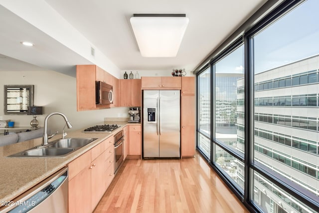 kitchen featuring sink, expansive windows, light wood-type flooring, appliances with stainless steel finishes, and light brown cabinets