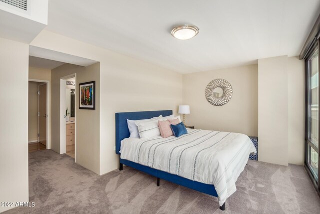 bedroom featuring ensuite bath and light carpet