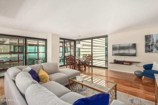 living room with a wealth of natural light, a wall of windows, and wood-type flooring