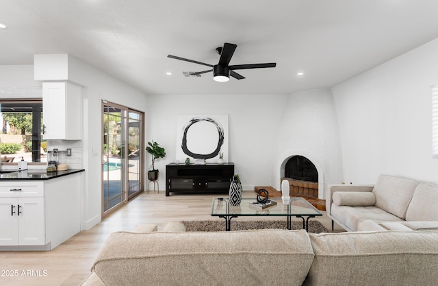living room featuring light wood finished floors, recessed lighting, a fireplace, and ceiling fan
