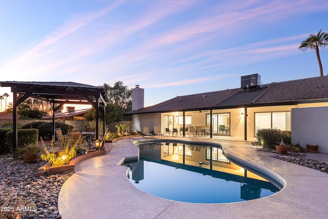 pool at dusk featuring a gazebo, a patio, an outdoor pool, and fence