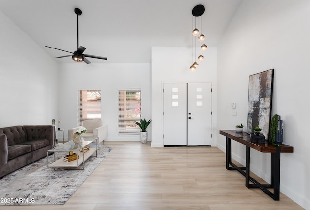 entryway featuring high vaulted ceiling, ceiling fan, light wood-style flooring, and baseboards