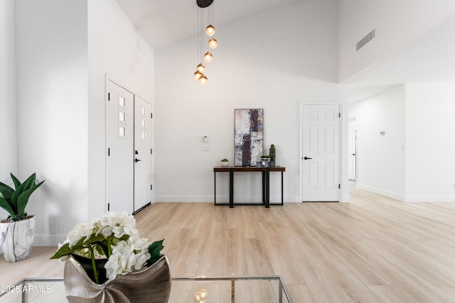 foyer entrance featuring high vaulted ceiling, light wood finished floors, and baseboards