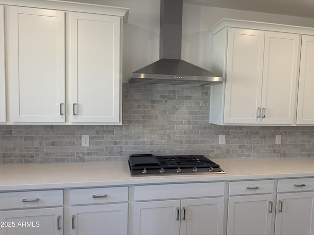 kitchen with white cabinets, light countertops, wall chimney range hood, backsplash, and stainless steel gas stovetop