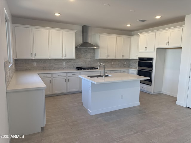 kitchen with double wall oven, light countertops, visible vents, a sink, and wall chimney exhaust hood