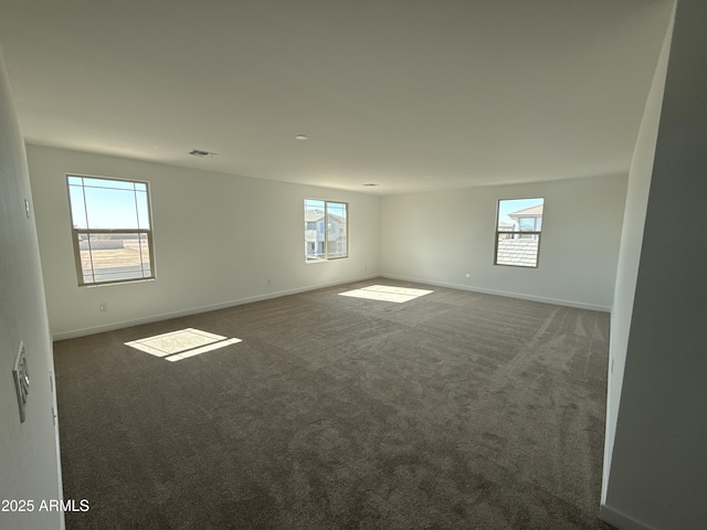 empty room with carpet flooring, visible vents, and baseboards