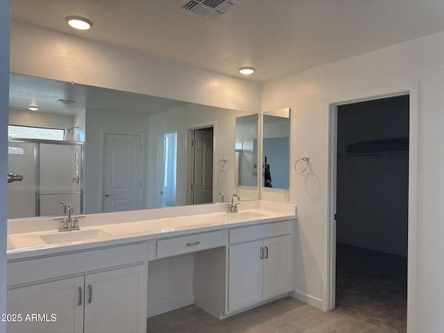 full bathroom with double vanity, a shower stall, visible vents, and a sink