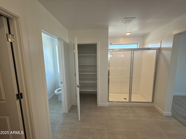 bathroom with a stall shower, baseboards, visible vents, toilet, and tile patterned flooring