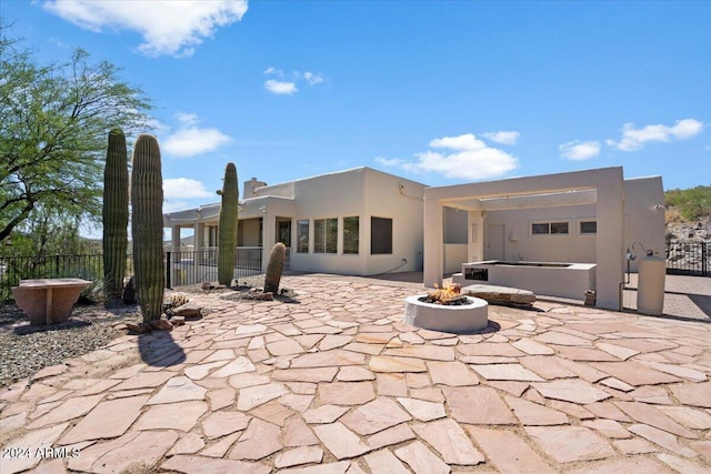 back of house featuring a hot tub, a patio area, and a fire pit