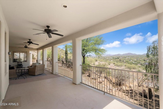 view of patio featuring a balcony, ceiling fan, and a mountain view