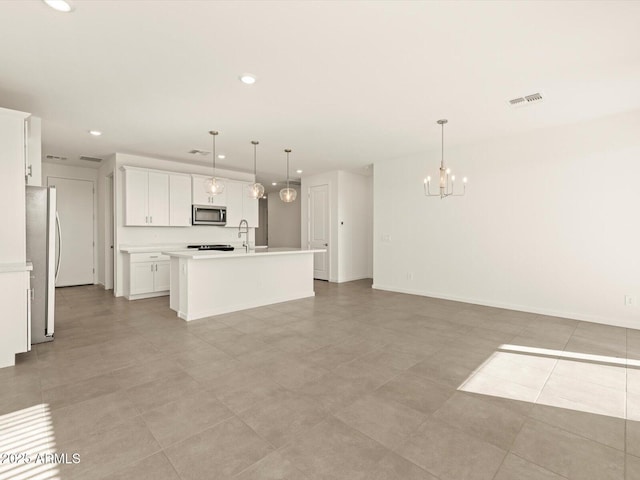 kitchen featuring appliances with stainless steel finishes, decorative light fixtures, white cabinetry, a kitchen island with sink, and a chandelier