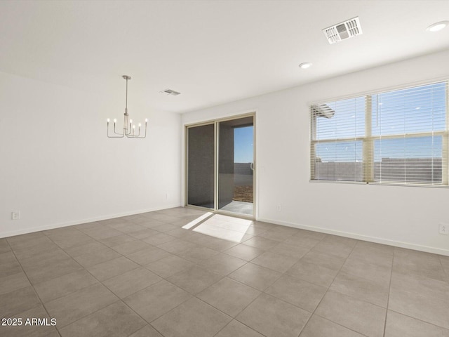 empty room featuring tile patterned flooring and an inviting chandelier