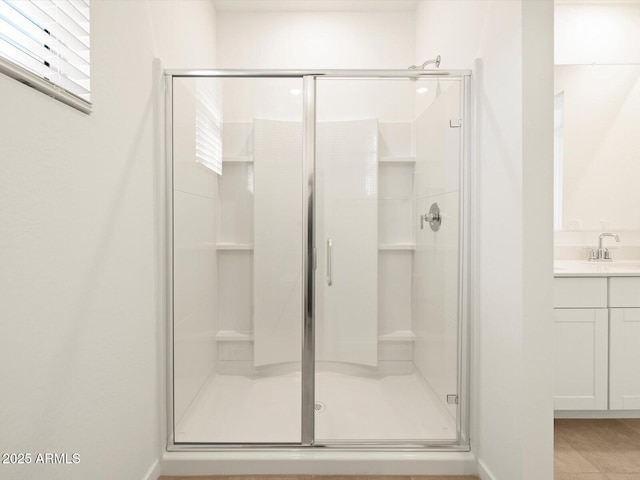 bathroom featuring a shower with shower door and vanity